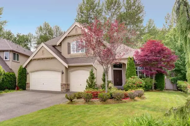 Farmington Garage Door Repair. Lovely American home exterior with gray stucco, stone elements, attached garage and perfectly kept front yard.