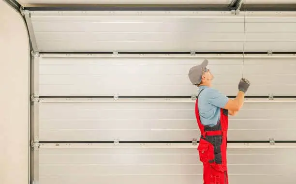 Automatic Residential Garage Doors Installation Performed by Professional Caucasian Technician in His 40s.