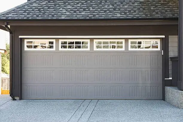 A gray garage door with windows across the top panel.