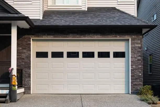 Garage Door. Modern house with garage door that is closed. A perfect neighborhood. Family house with wide garage door and concrete driveway in front. Street photo, nobody