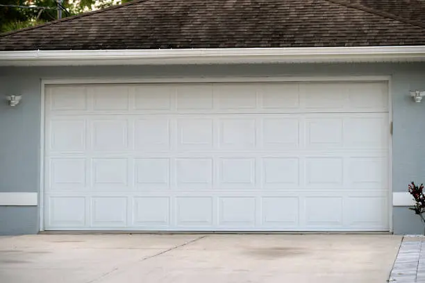 Wide garage double door and concrete driveway of new modern American house.