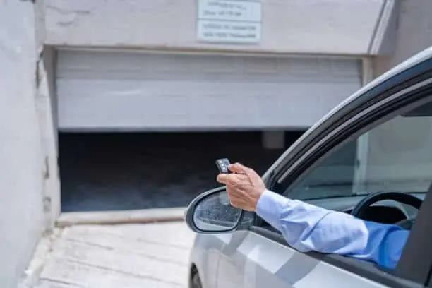 Man In Car Using Remote Control To Open The Automatic Garage Door