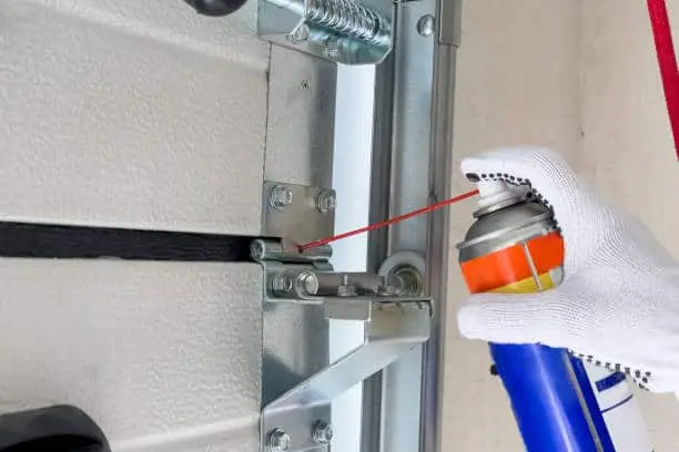 A worker lubricates sectional doors after installation in a garage. The concept of lubrication of sectional doors.