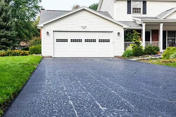 One day after a brand new residential home blacktop asphalt driveway was completed - with overnight rain puddles beading on the slippery, still oily surface.