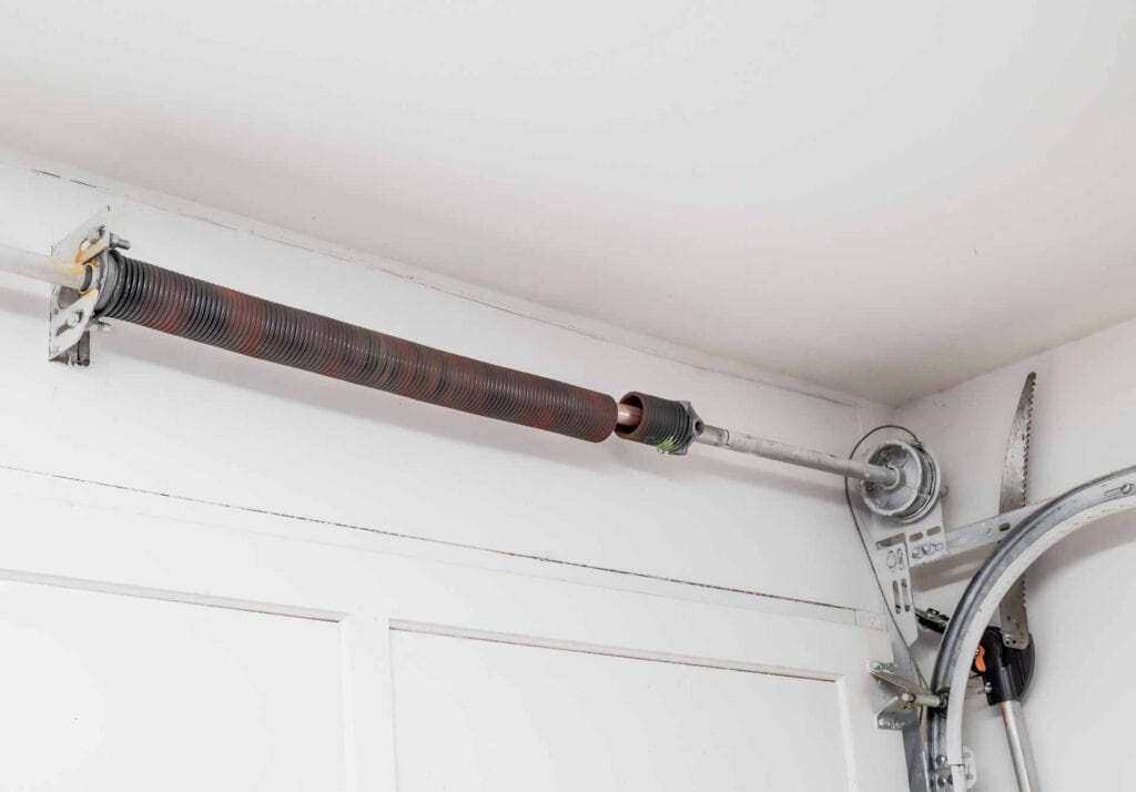Broken garage door spring above a closed garage door.
