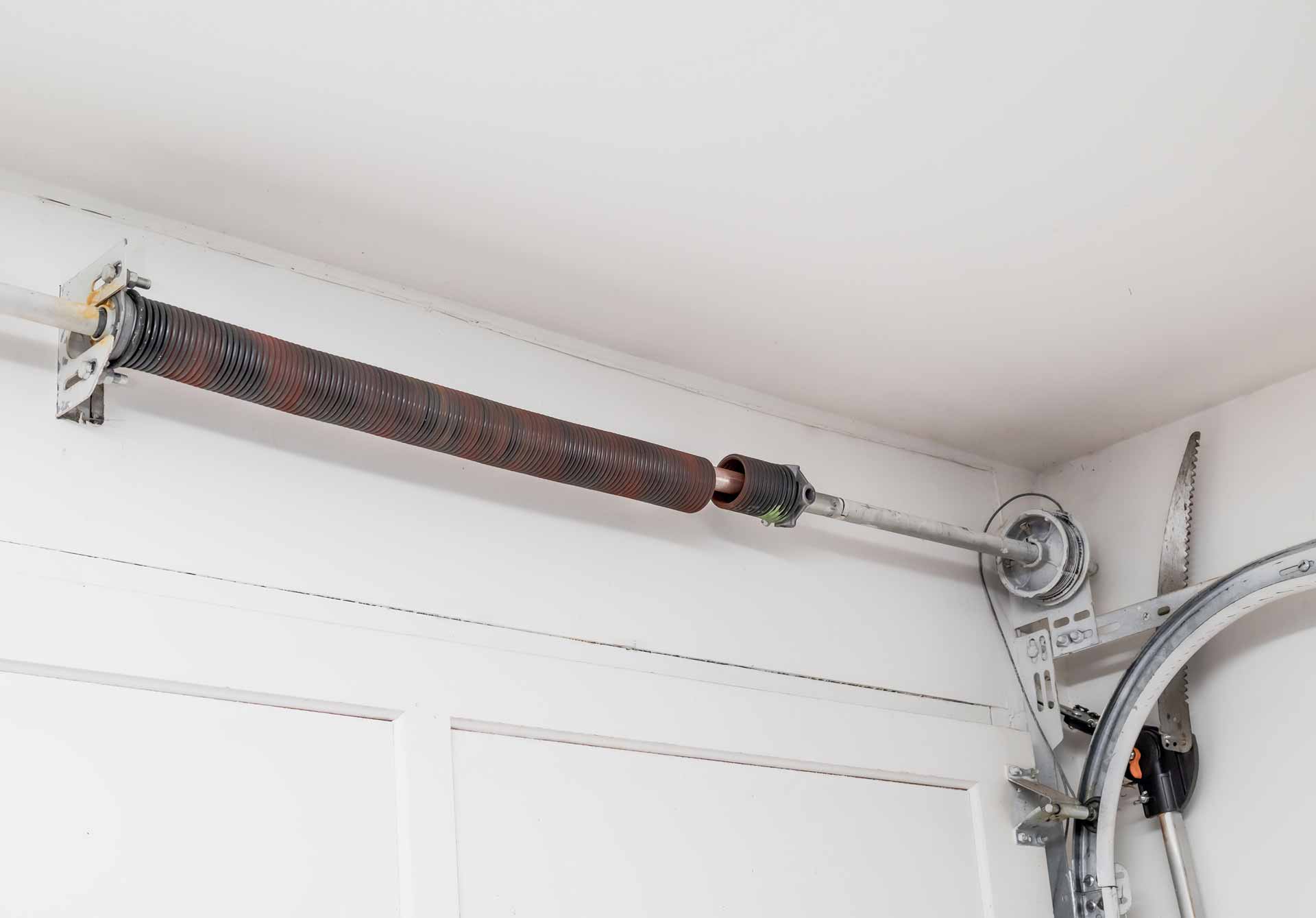 Broken garage door spring above a closed garage door.