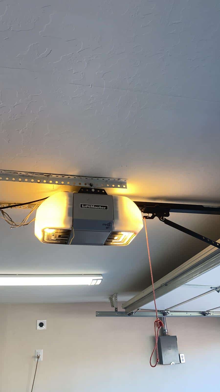 A garage door opener inside an open garage door. The light in the opener is on. Michigan Door