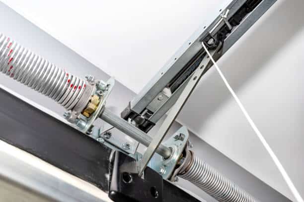 Springs tensioning the home garage door mechanism, visible disconnection of the electric drive and spring protection. East Lansing Garage Door Repair