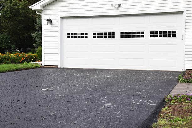 White house with white garage door and beautiful landscaping on the side.