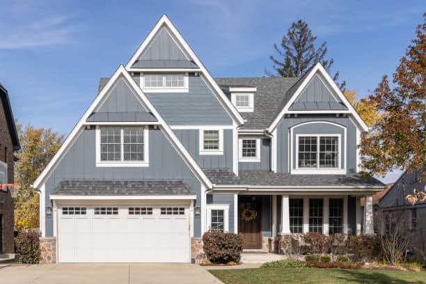 A blue and white modern farmhouse with a covered porch, grey roof, and two car garage.