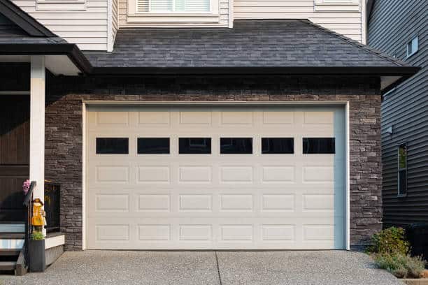 Garage Door. Modern house with garage door that is closed. A perfect neighborhood. Family house with wide garage door and concrete driveway in front. Street photo, nobody