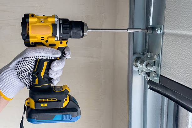 A garage door repair technician assembles sectional doors using a screwdriver. The concept of sectional door installation.