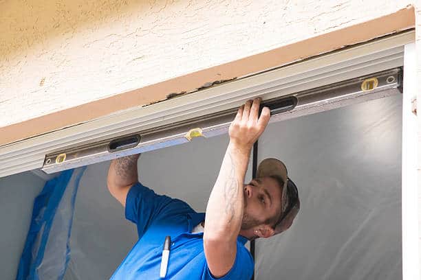Caucasian male is using a level to check that the new frame has been properly installed.