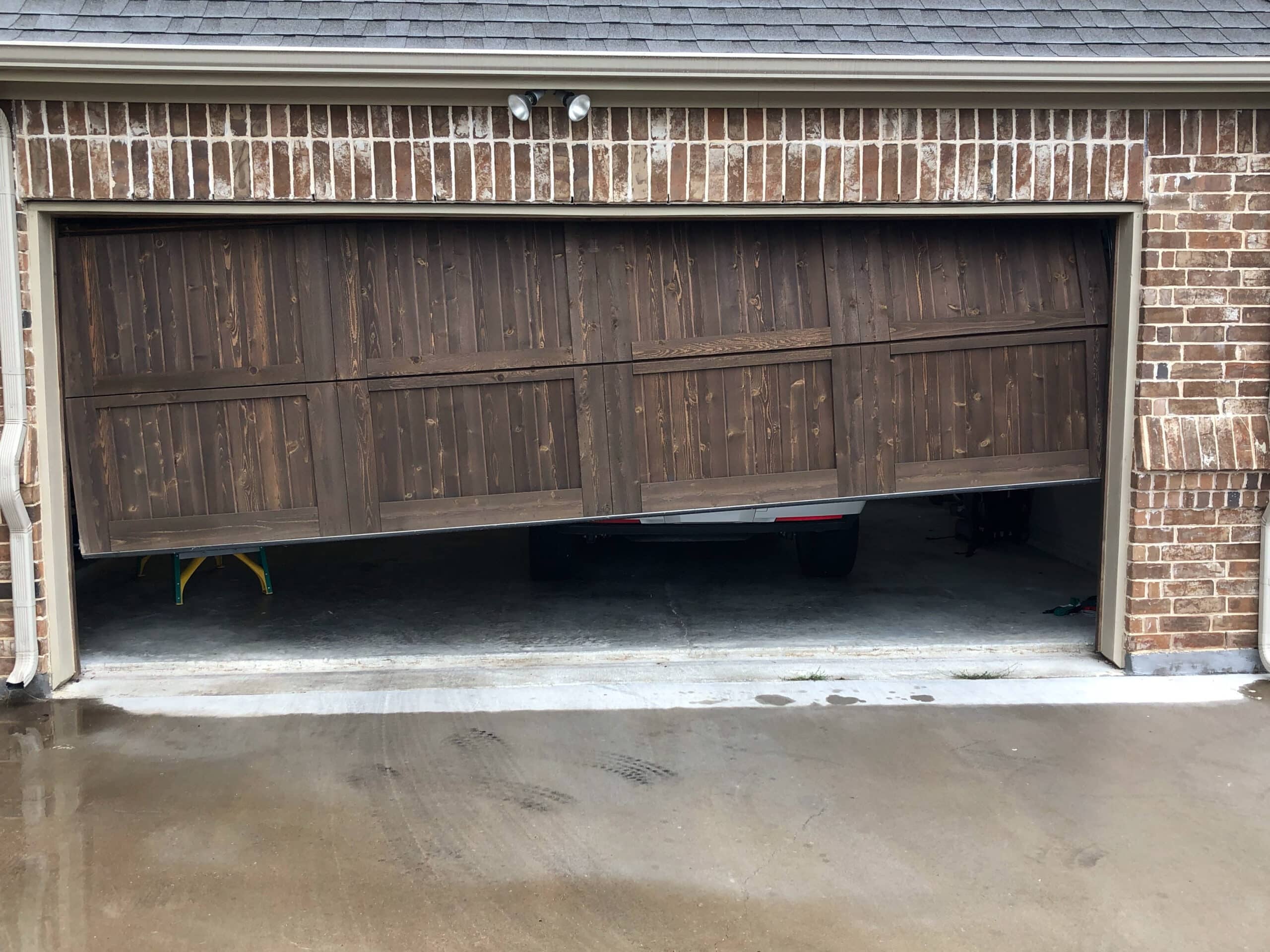 A wooden garage door hanging lower on one side.