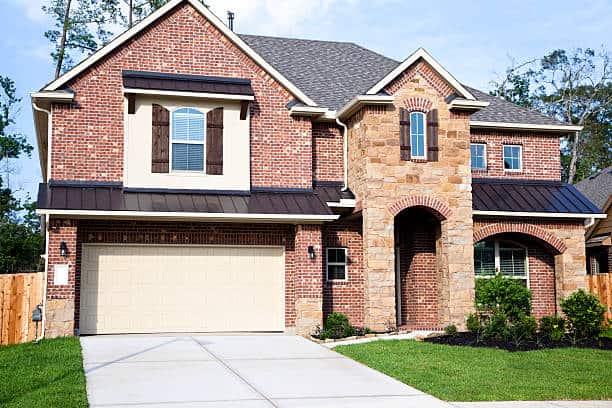 Red brick house with tan garage door.