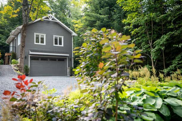 Luxurious gray and white two-story detached double garage located in Quebec, Canada during summer.