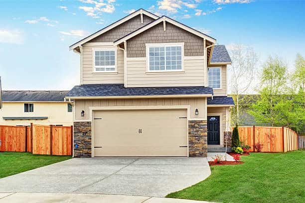 American house exterior with beige trim, garage with concrete driveway and brown fence with well kept lawn around